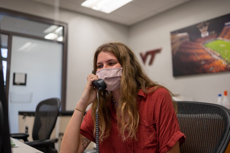 Charity Hall sits in the front office of Housing and Residence Life and has a conversation on the phone with a student. Photo by Luke Williams for Virginia Tech.