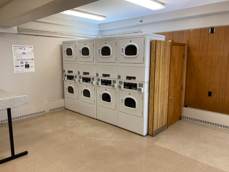 Laundry facilities, with four sets of washers set along a wooden wall.