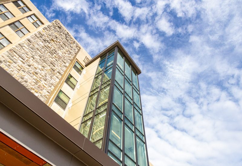 A view looking up at the sky that includes the large glass staircase in the front of O'Shaughnessy Hall.